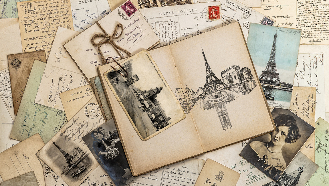 Vintage photographs, postcards and a notebook lie on a table. 