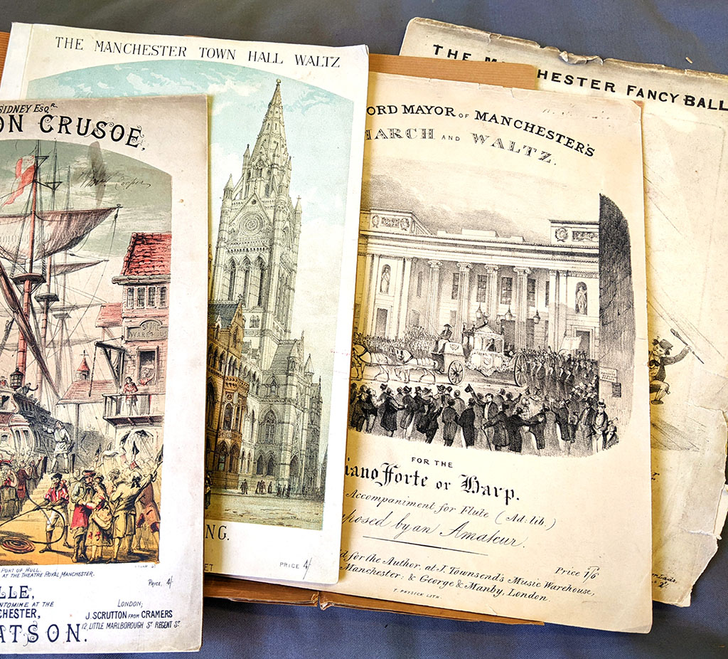 Song sheets from the 1880s are laid out on a table.