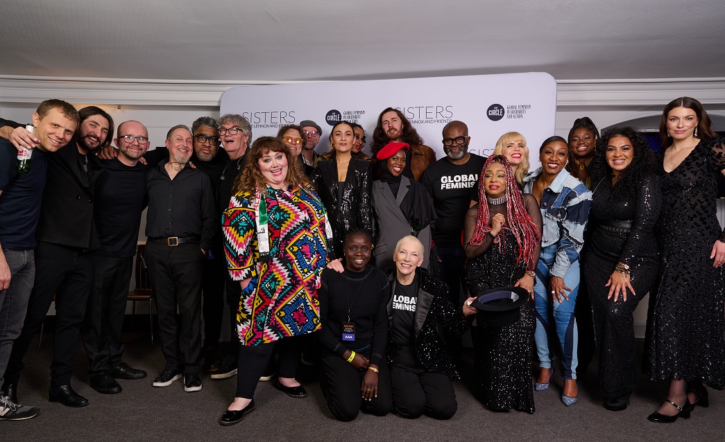 Annie Lennox crouching down with a group of performers behind her