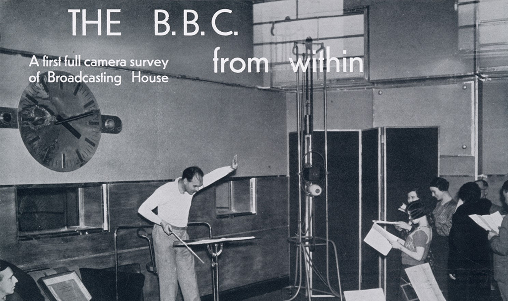 A 1930s era photograph shows a conductor leading a choir in a BBC studio.