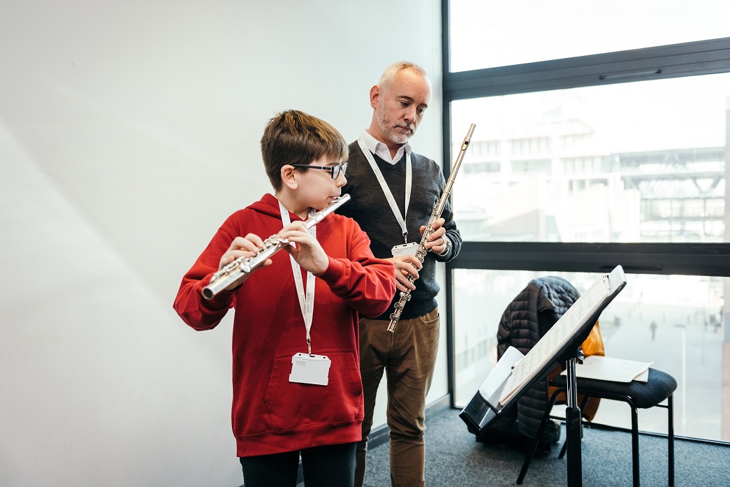 Young flautist practicing with flute tutor.