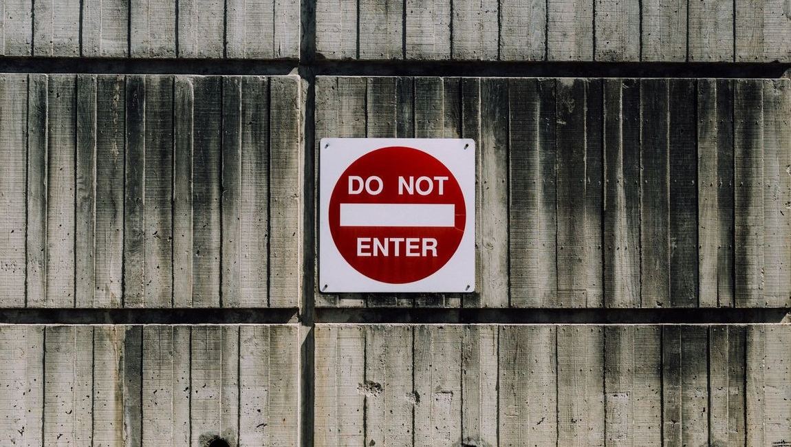 A sign that reads "do not enter" is fixed to a wooden fence. 