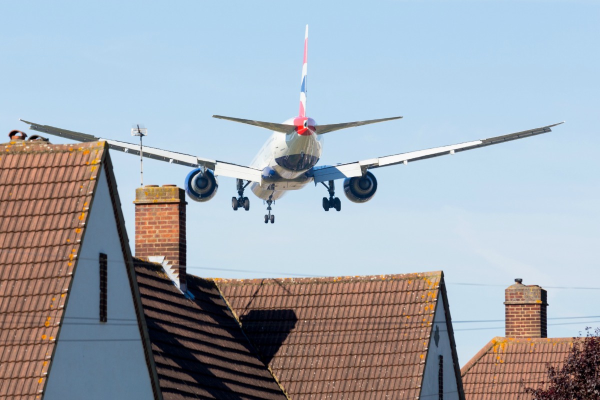 A aeroplane flies over the roof of a house.