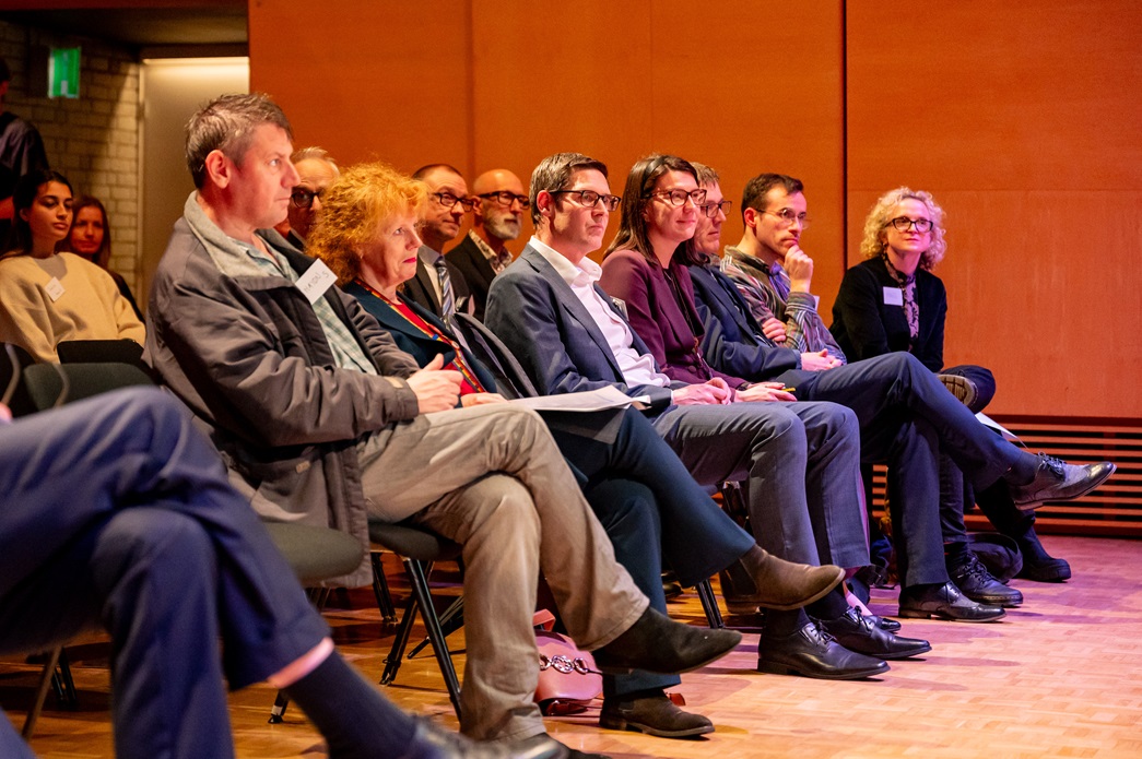 A row of people sitting down watching a speech
