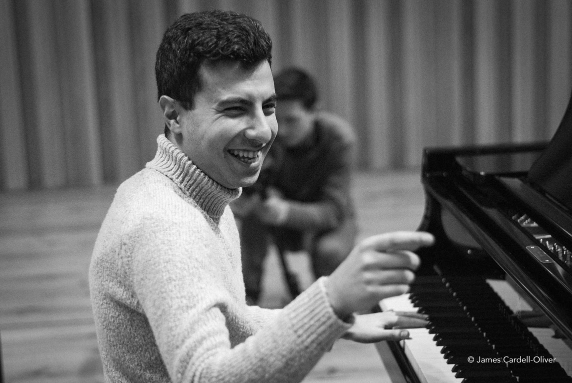 Iyad Sughayer sitting at the piano laughing