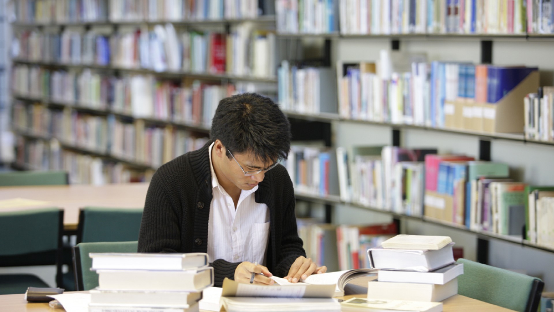 A student studies at a desk in the RNCM library surrounded by books. 