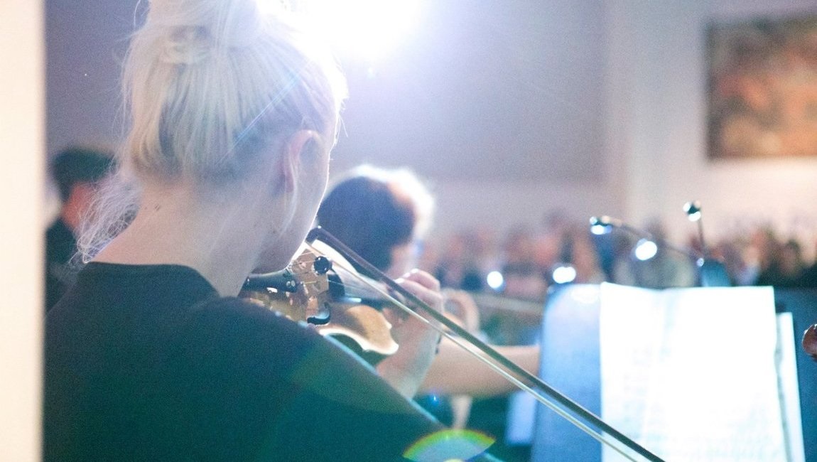 Over the shoulder of a violinist for the BBC Philharmonic as she plays from a music stand. 