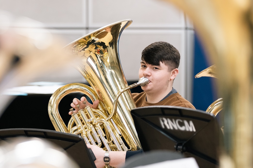 RNCM young tuba player sitting in an ensemble