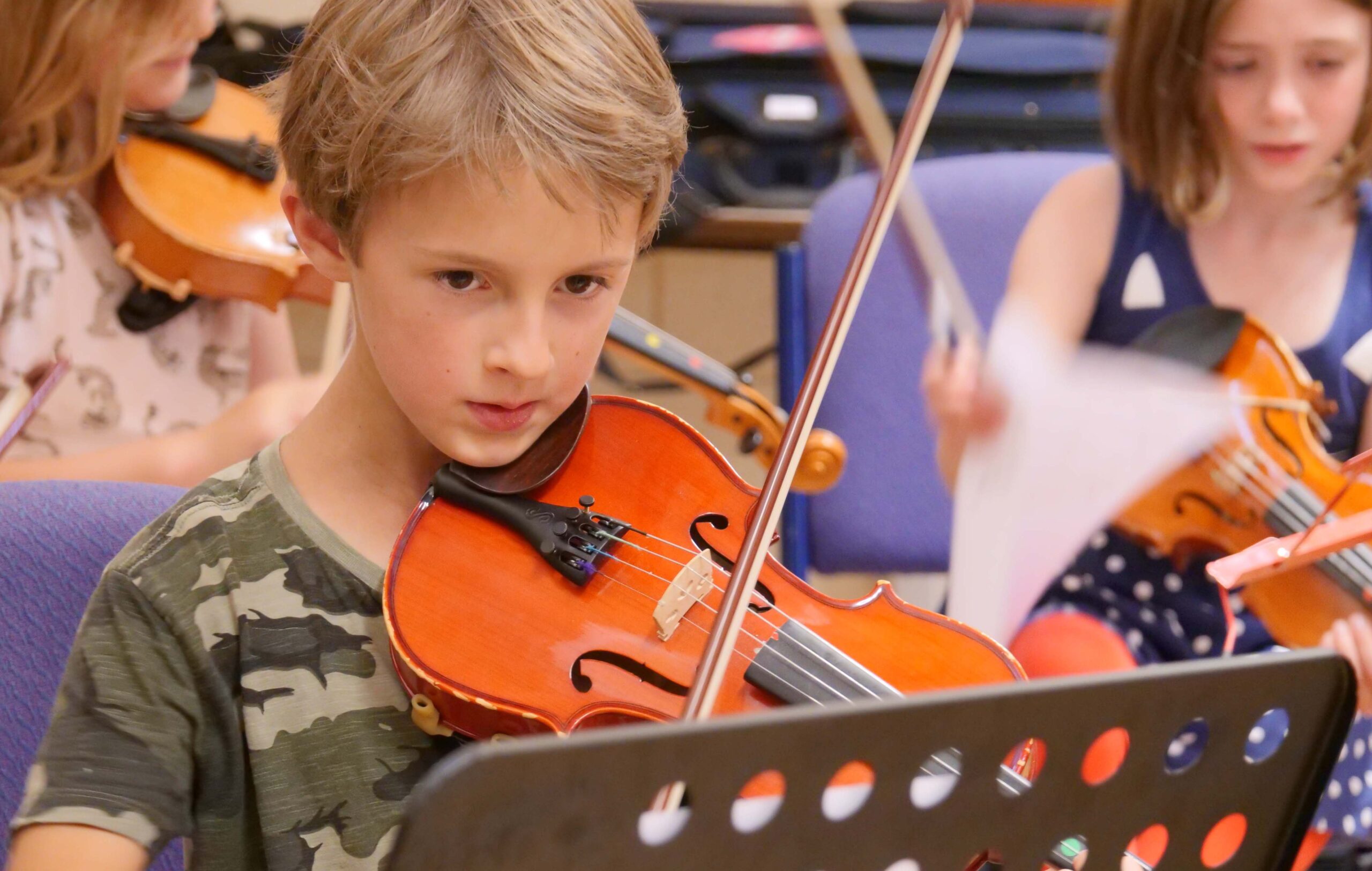 A child concentrates on his sheet music as he plays the violin in a Junior RNCM string orchestra. 