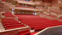 A large theatre filled with red seats at Poly Arts campus.