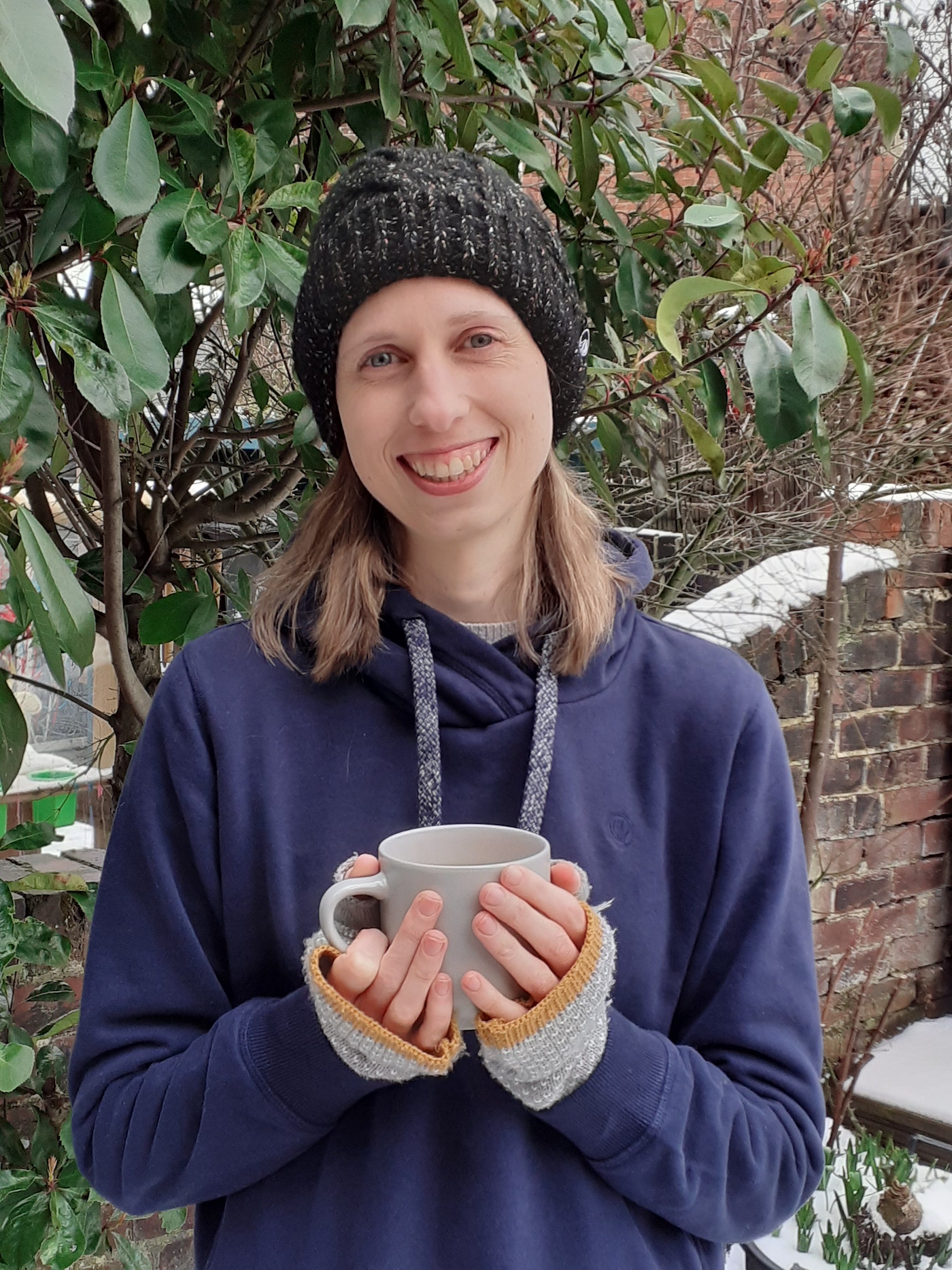 A woman outside holding a warm drink in a mug