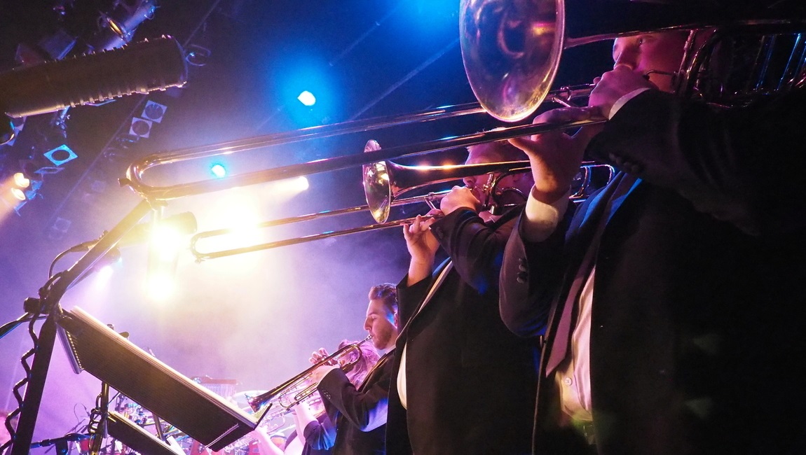 Students dressed in suits play trumpets during a performance. 