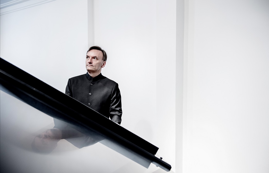 Sir Stephen Hough standing at a piano