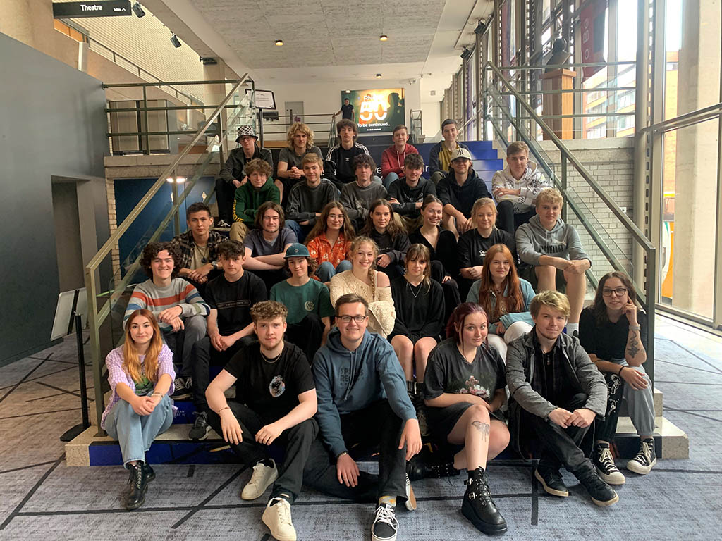 The 2023 Summer school participants sit on the stairs of the RNCM. 