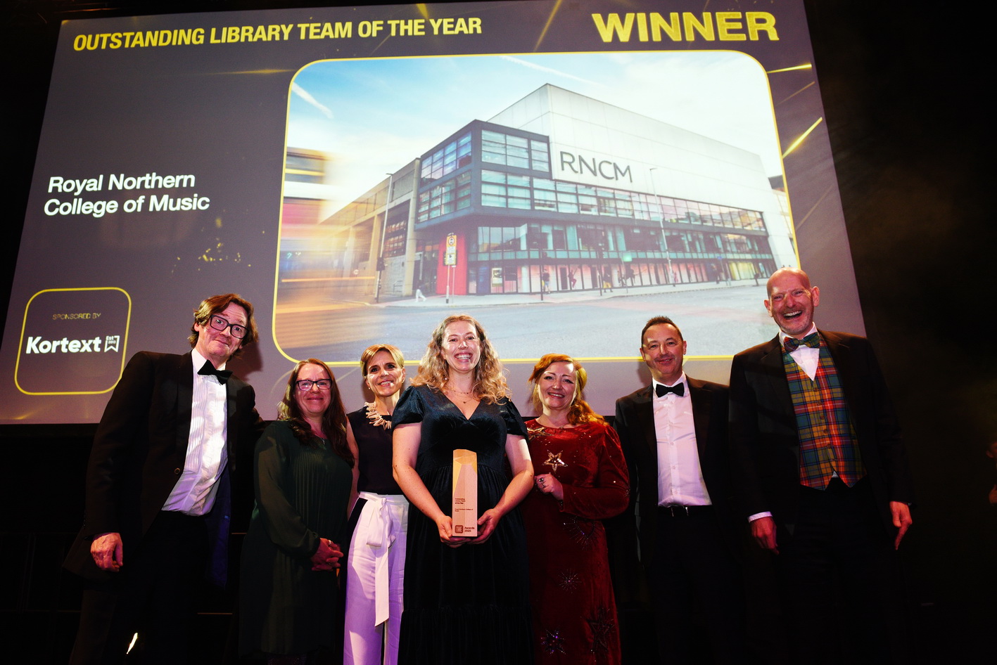 RNCM library team standing in front of a big screen announcing the win