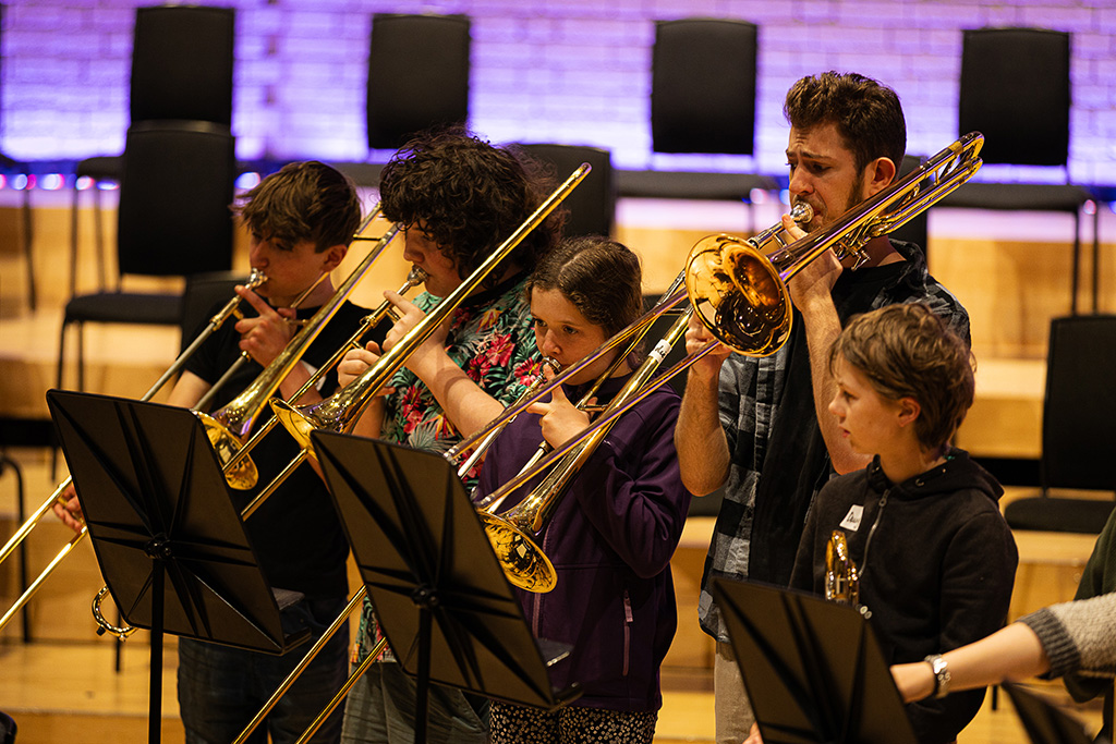 Young projects students play trombones.