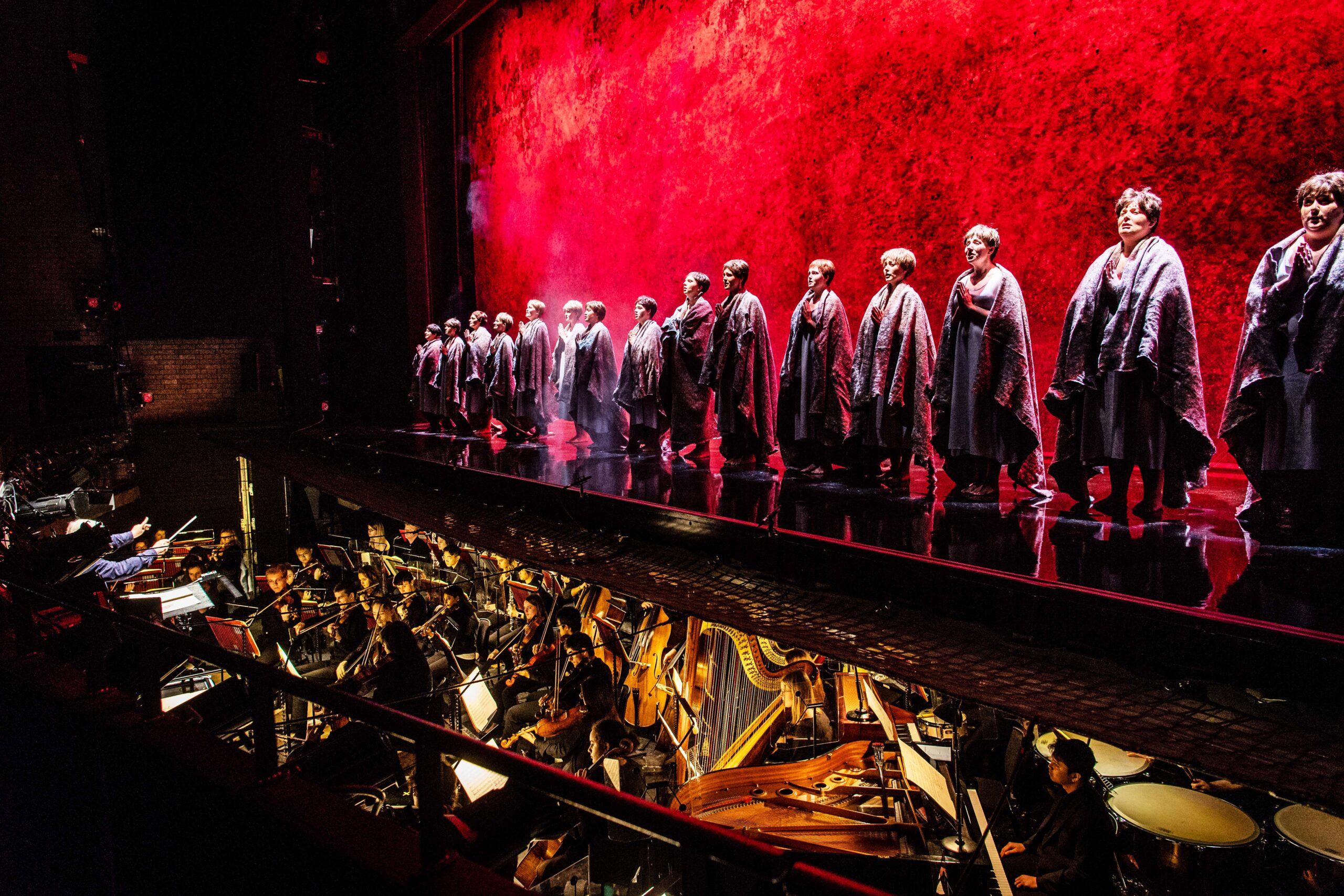 Women in shawls stand in a line on stage during a performance of the opera Dialogues des Carmelites.