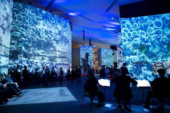 Images of victims of Hiroshima are projected on the walls of museum as a quartet plays and visitors watch. 