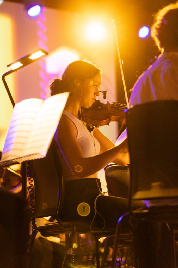Violinist on stage under a bright light.