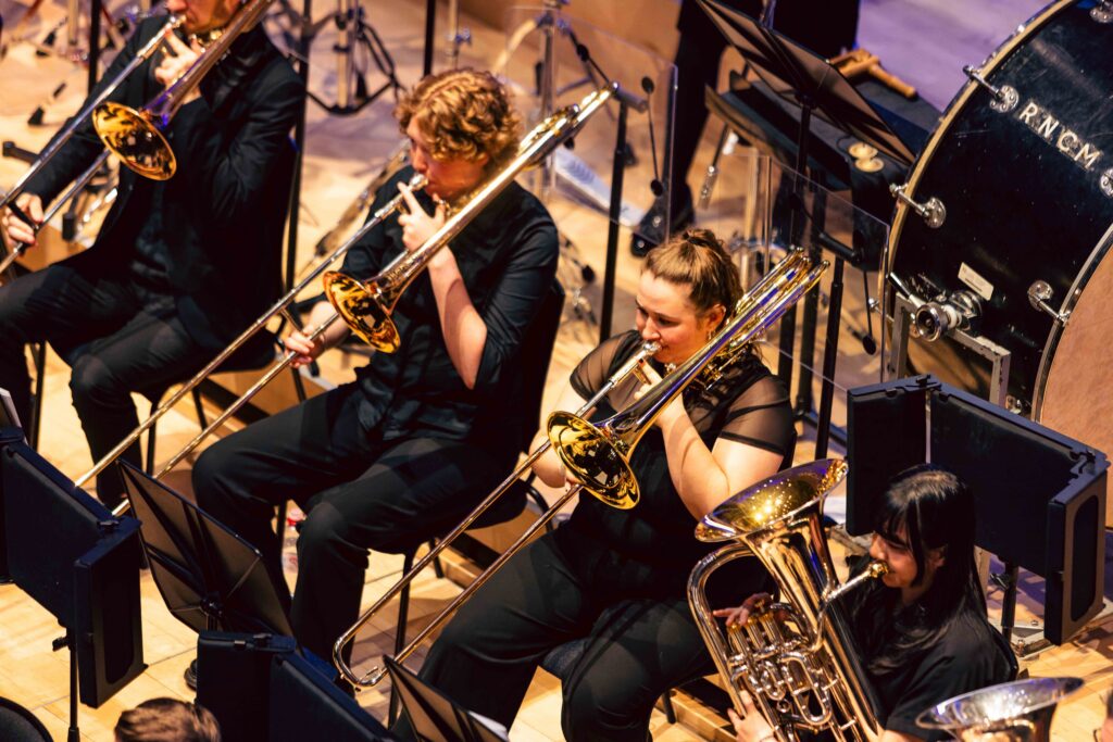 RNCM brass musicians performing in an orchestra.