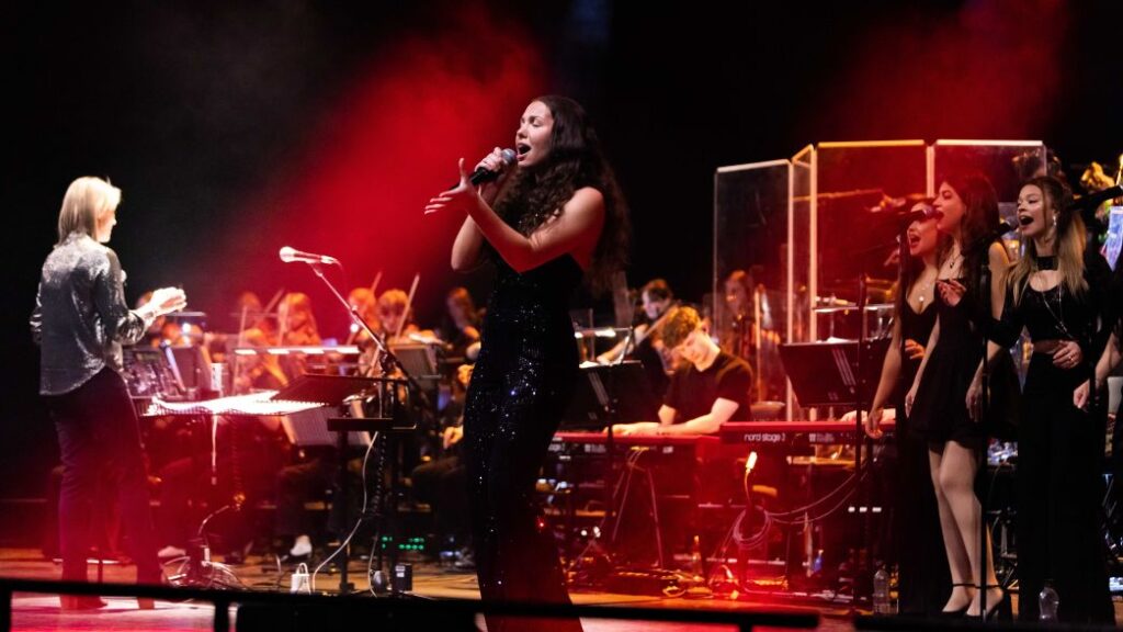 female singer performing on theatre stage with red lights