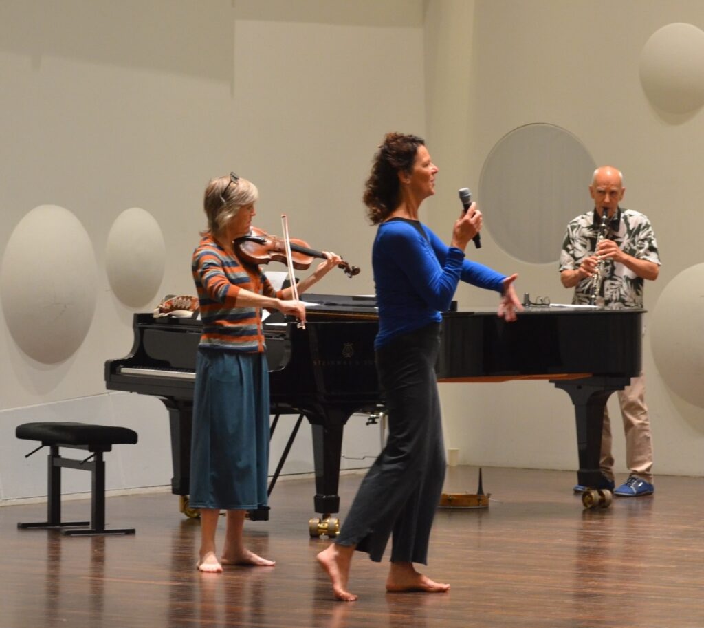 A trio of musicians perform in from of a piano.